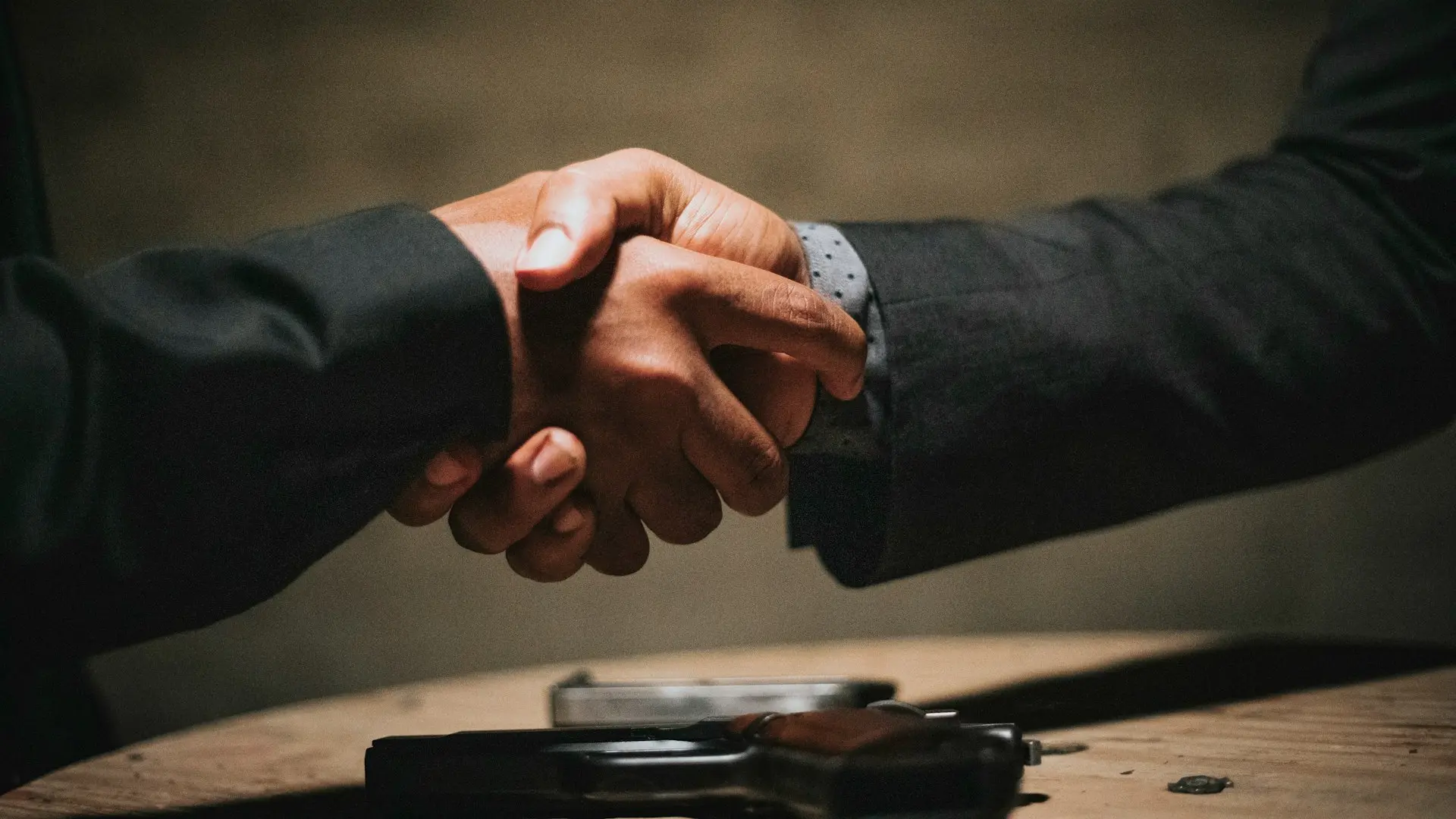 two people shaking hands over a wooden table