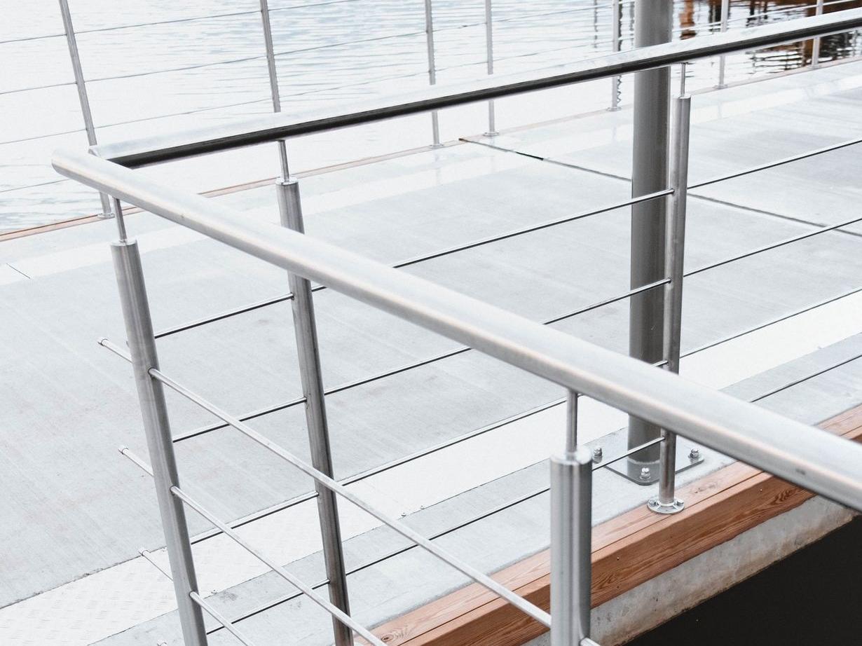 China-sourced stainless steel railing system with vertical posts and horizontal cables tainless steel railing system with vertical posts and horizontal cables along a glass or concrete walkway, modern architectural railings.
