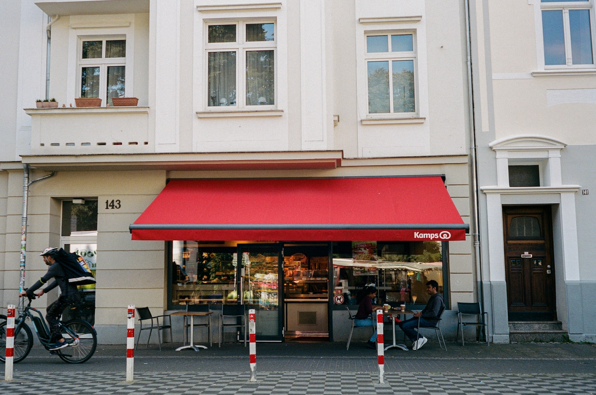 Red awning of a retail store a man riding a bike past a red awning