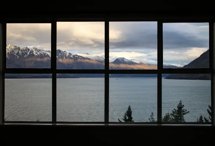 Windows calm body of water near brown mountain under white and gray sky