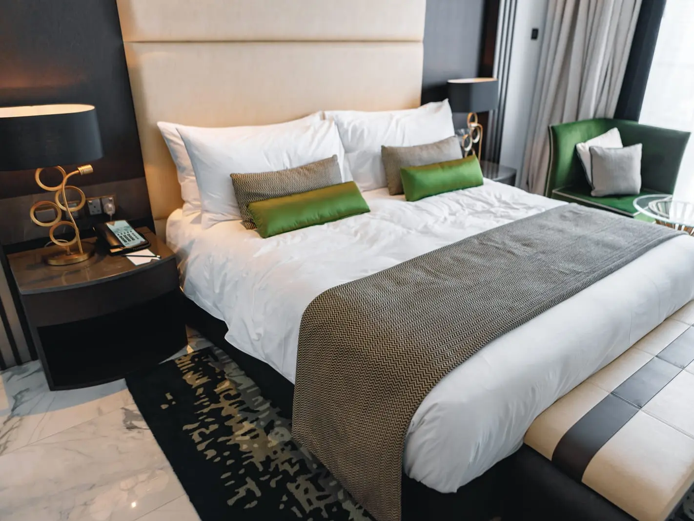 Hotel room with bed, chair, and green pillows