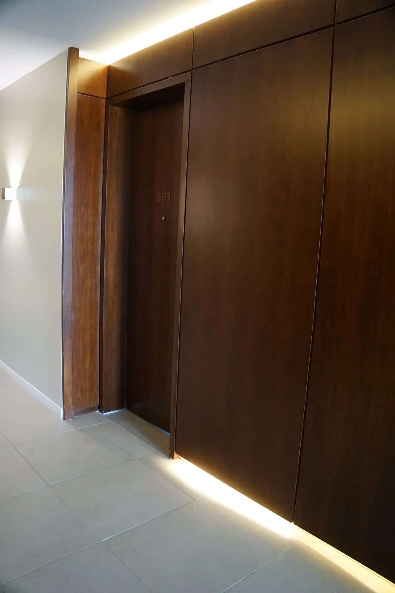 Modern wooden hotel door with room number 603 and ambient lighting.