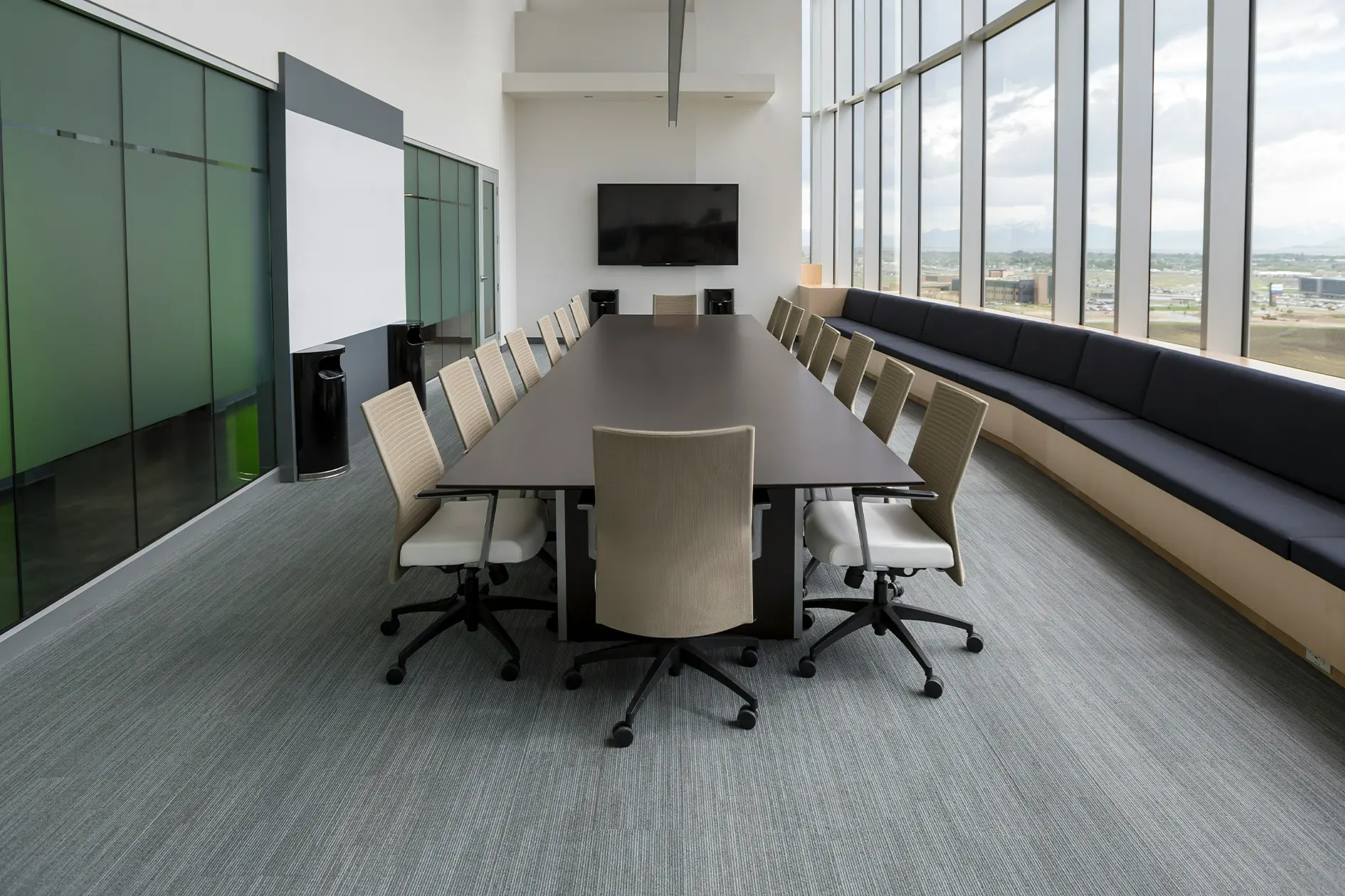 Contemporary office meeting room setup with conference table, ergonomic chairs, and large windows