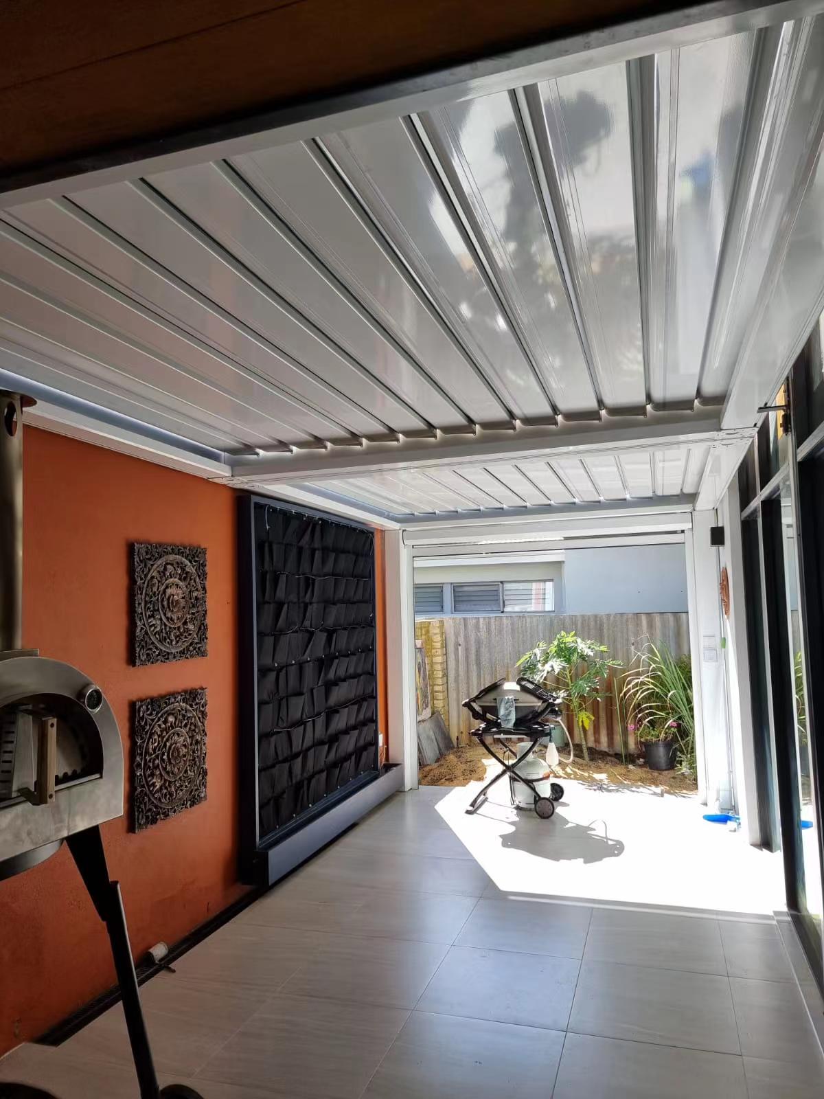  Interior view of a modern pergola with a sleek metal ceiling, featuring an outdoor space and decorative elements.