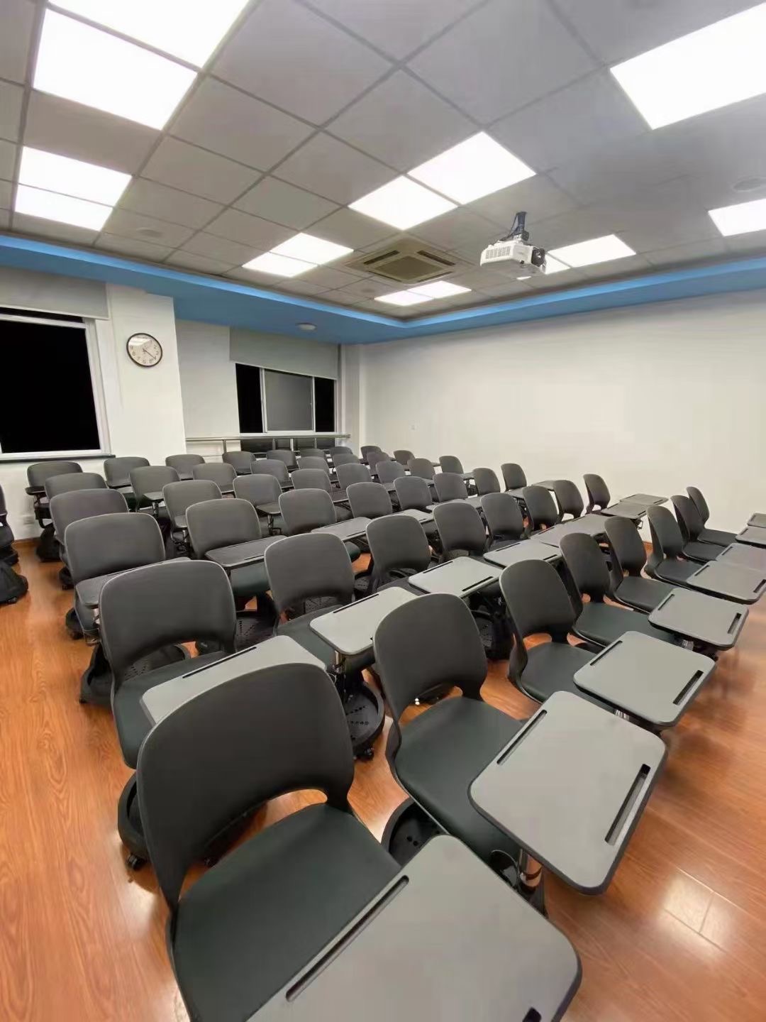 Classroom with modern school furniture, including rows of black chairs with attached writing surfaces.