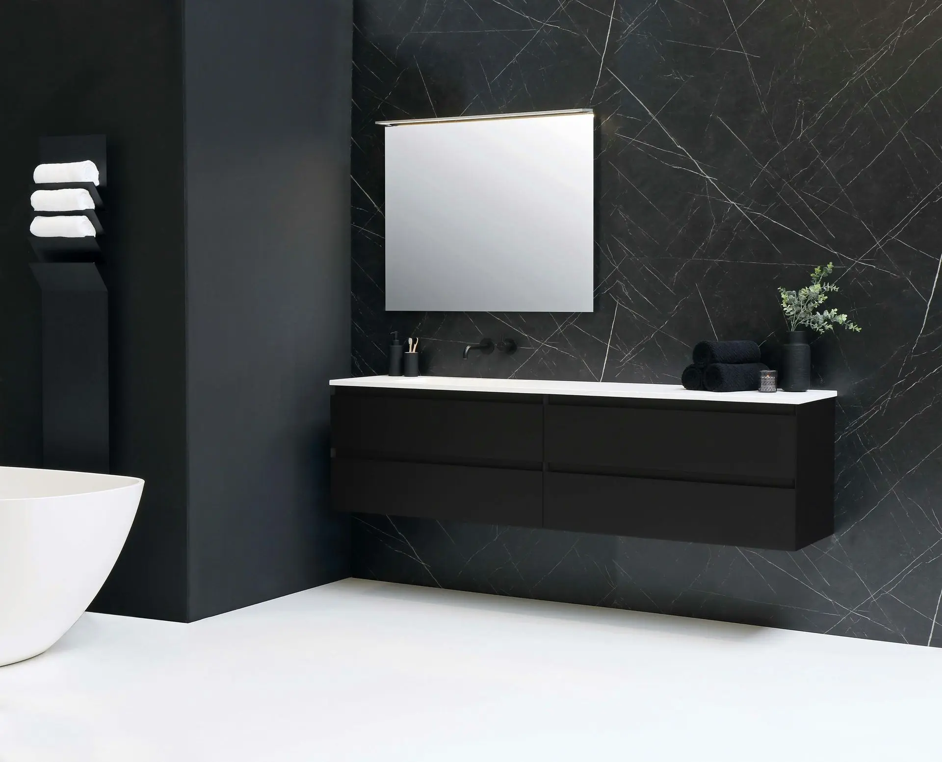 Modern black vanity unit with a mirror, white countertop, and decorative plants in a stylish bathroom.