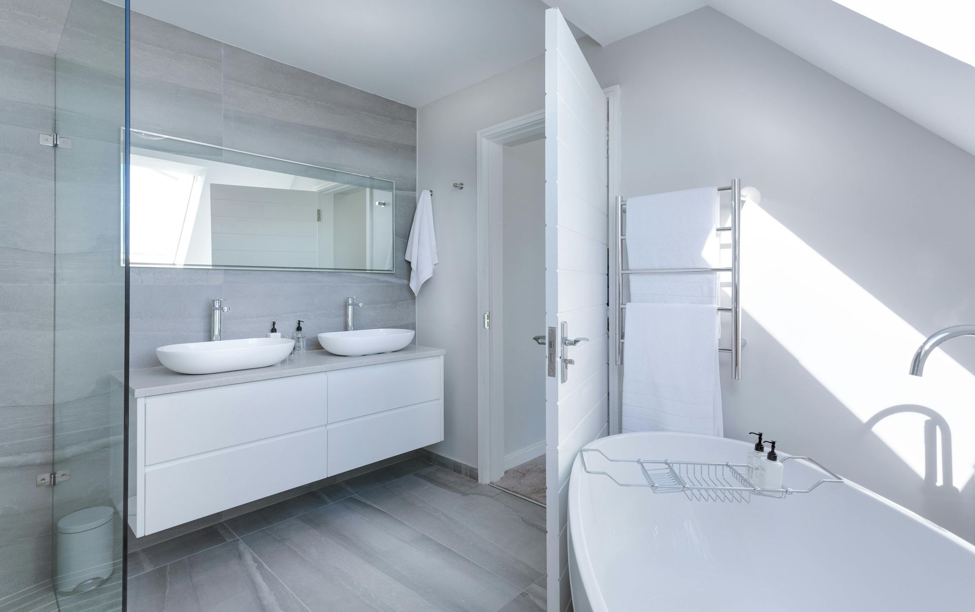Modern white vanity unit with double sinks and a large mirror in a bright, airy bathroom.