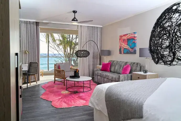 Stylish living area in a suite at the O2 Club and Spa, featuring ocean views, modern decor, and vibrant accents.