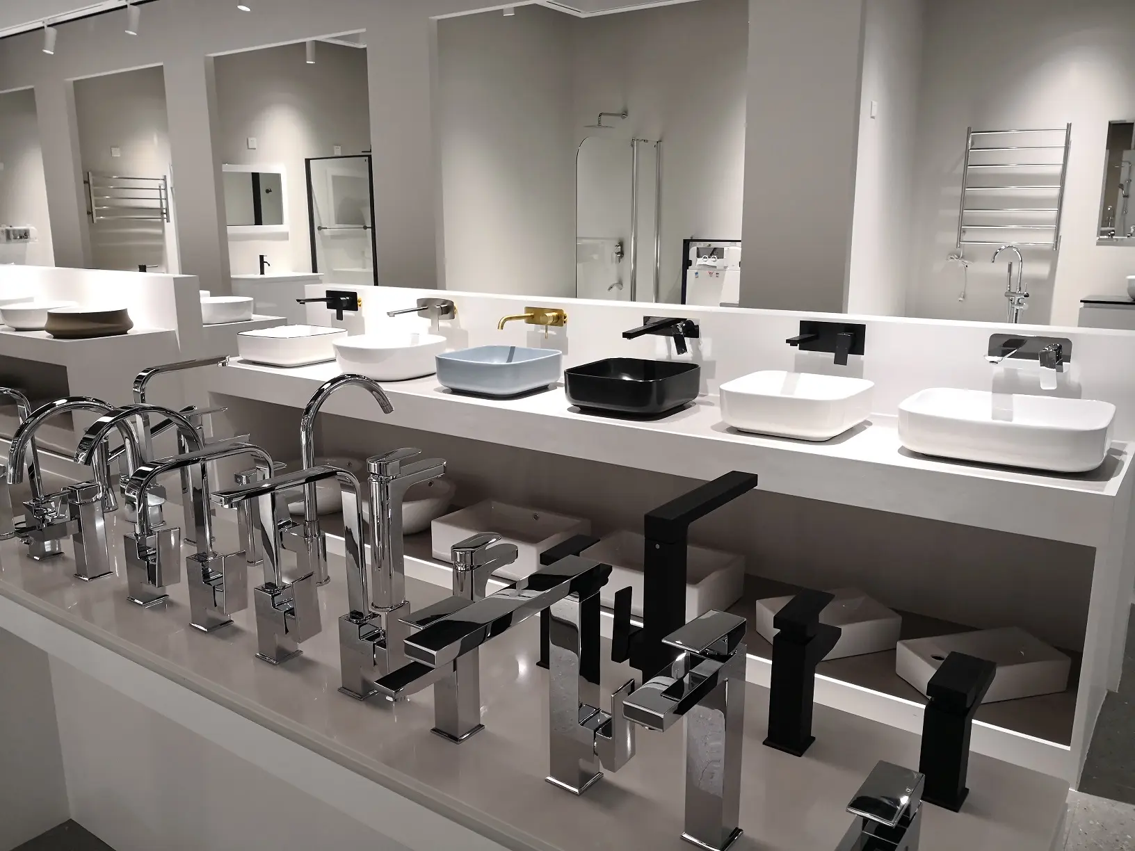Display of various modern bathroom faucets and sinks in sleek designs and finishes.
