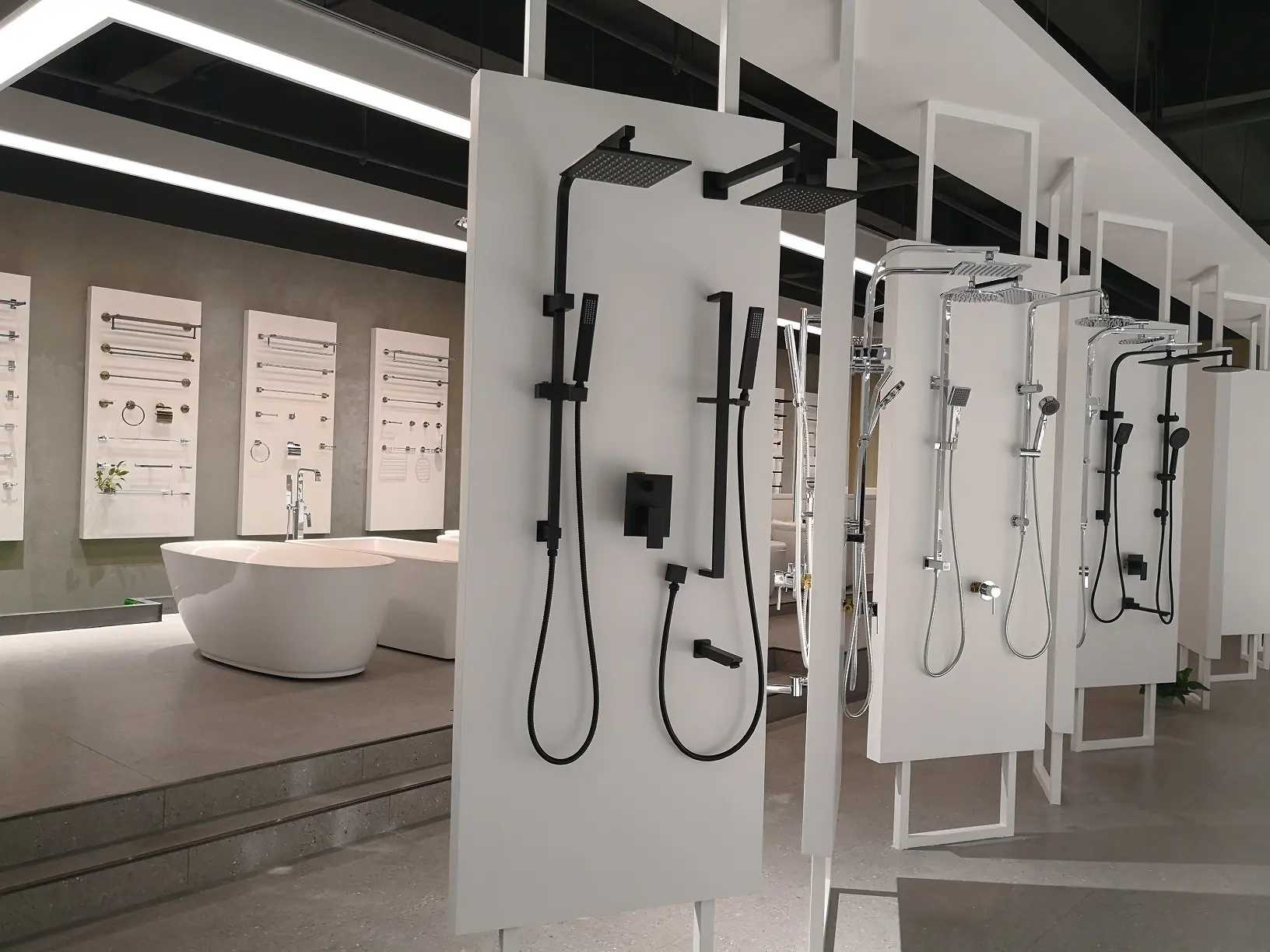 Modern showroom display featuring various sleek shower systems and fittings alongside a contemporary bathtub.