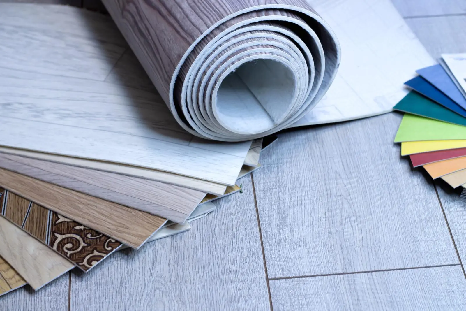 A selection of vinyl flooring samples, including rolled sheets and various styles, with color swatches for comparison.