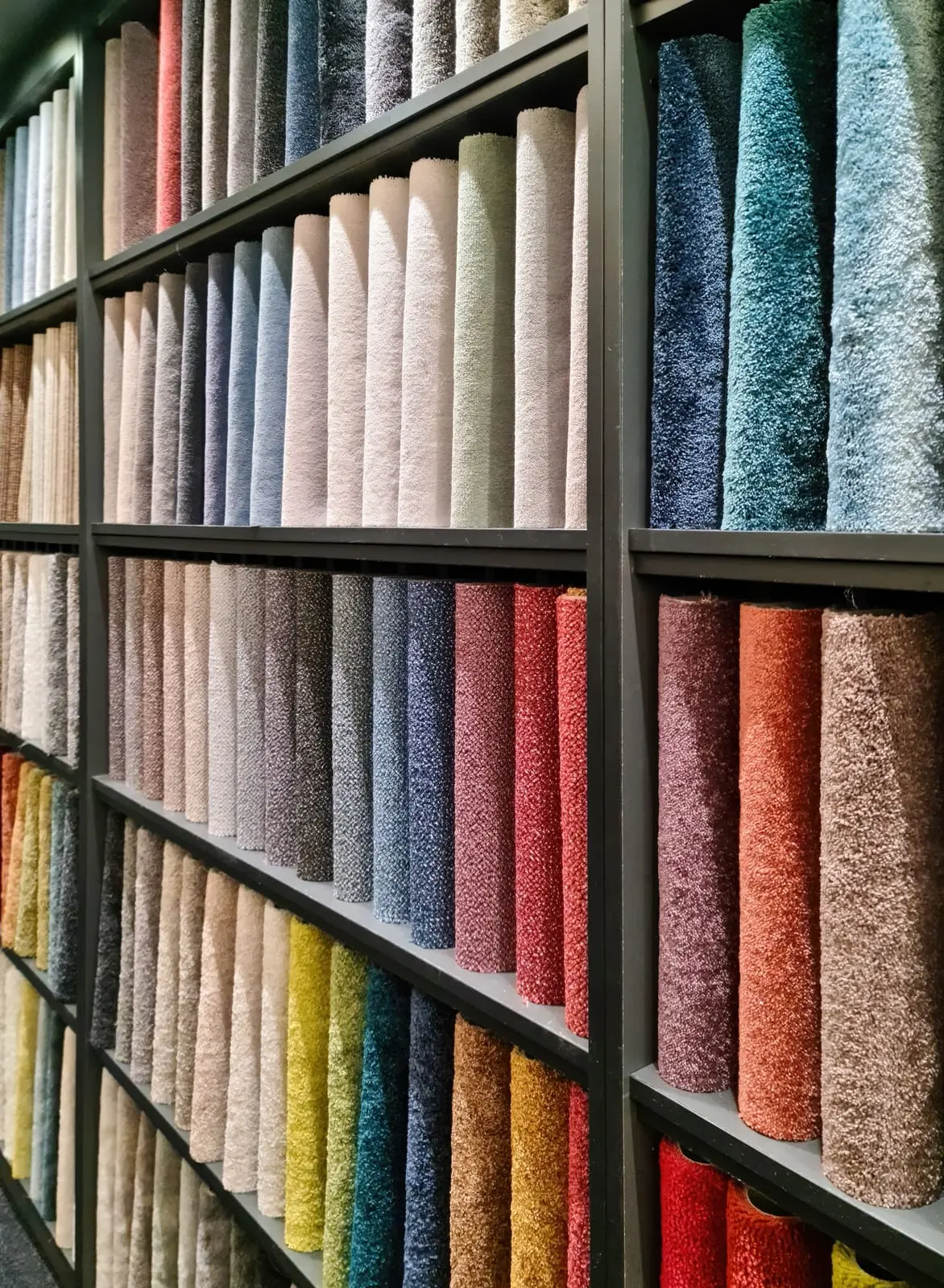 A display of rolled carpets and rugs in various colors and textures, showcasing the diversity of options available.