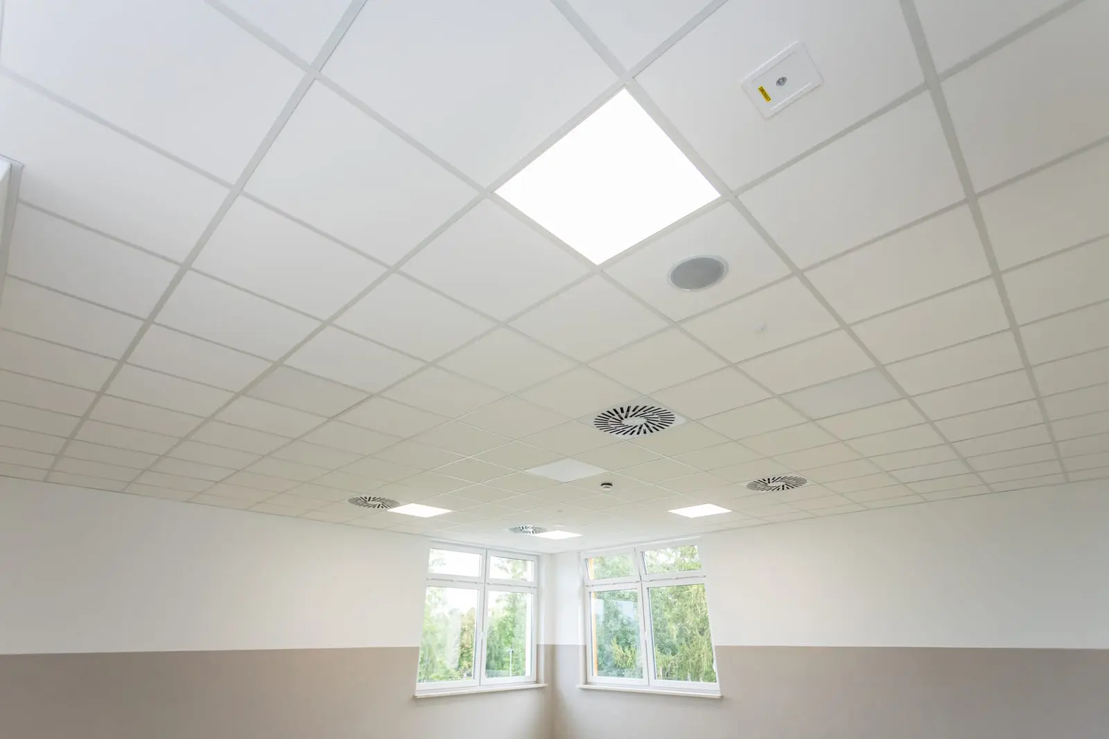 Interior view of a ceiling featuring mineral fiber tiles with integrated lighting and ventilation.