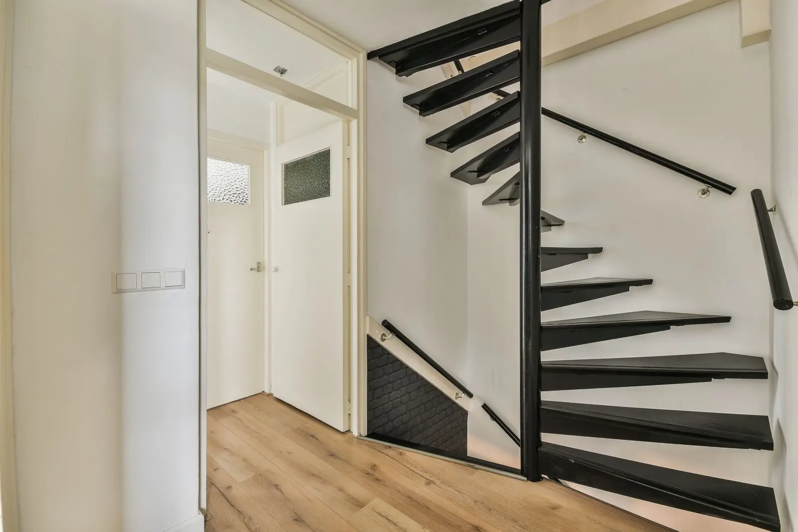 Stylish and Cost-Effective Stairs: Sourcing Options in China Spiral black staircase in a modern interior with wooden flooring and white walls.