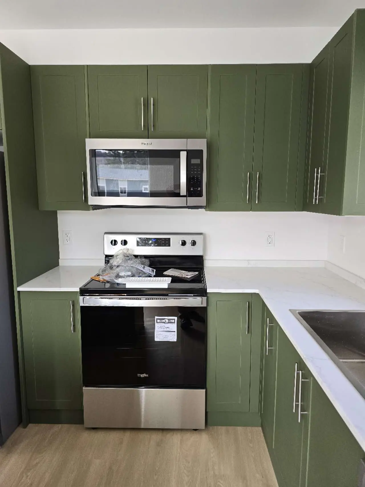Elegant kitchen area featuring green cabinetry, stainless steel appliances, and a marble countertop.