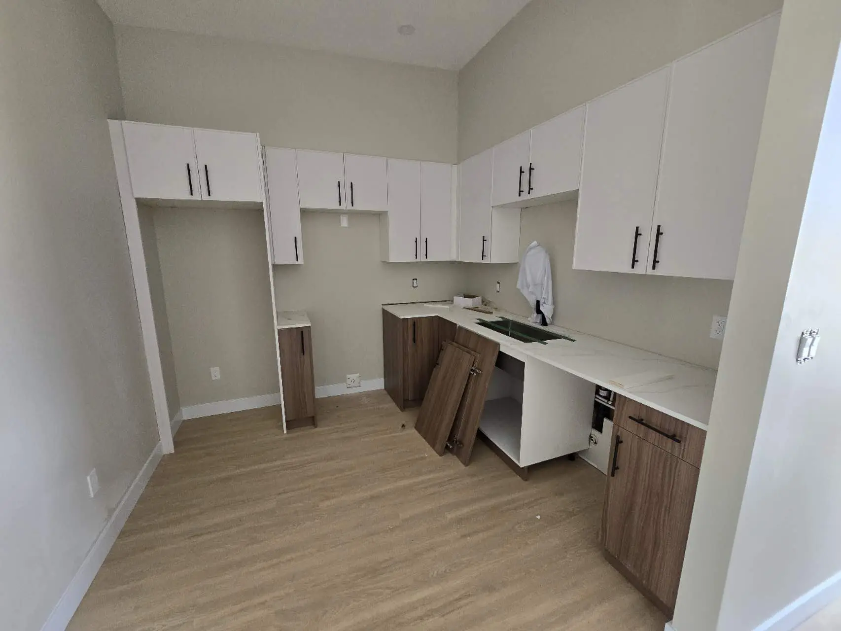 kitchen space with white and wood cabinetry, showcasing a countertop and an sink area.