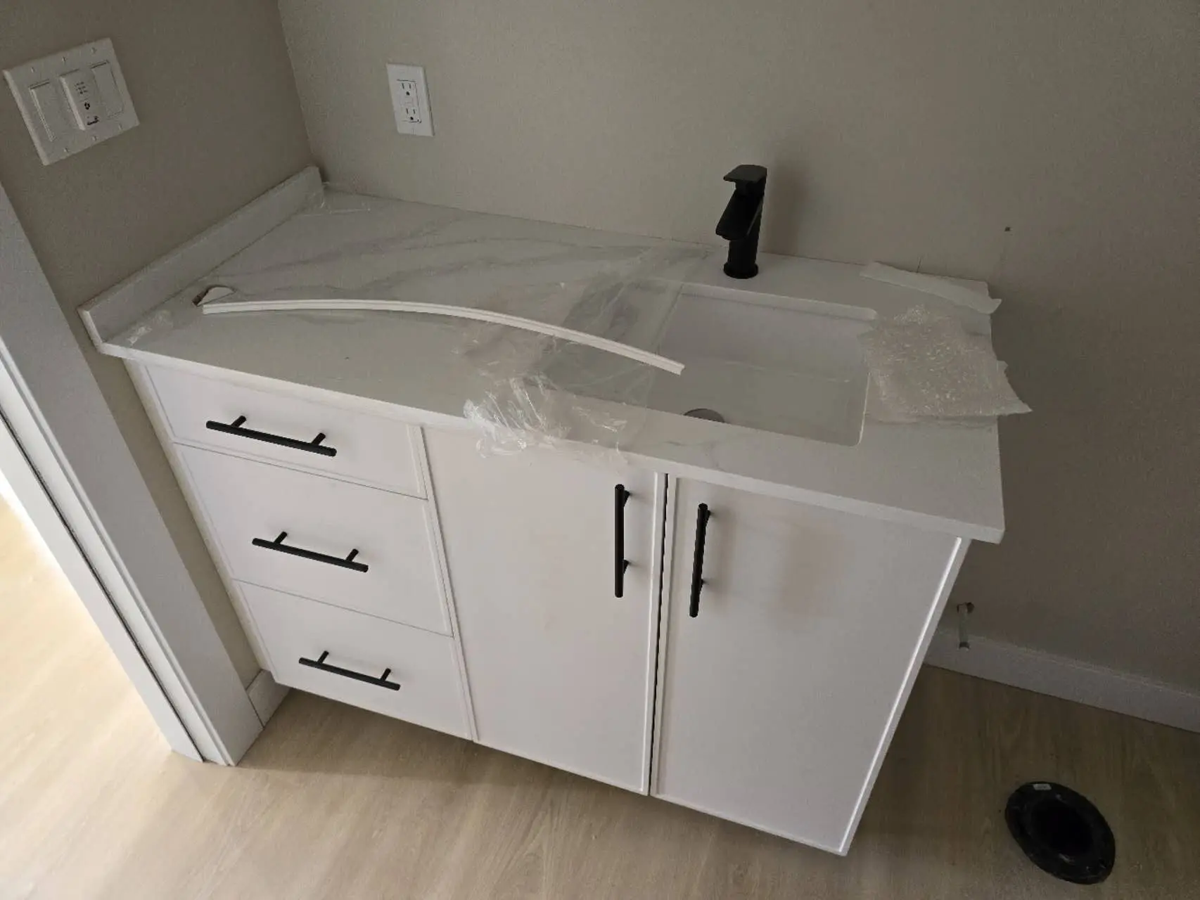vanity with a white marble countertop, black faucet, and storage drawers