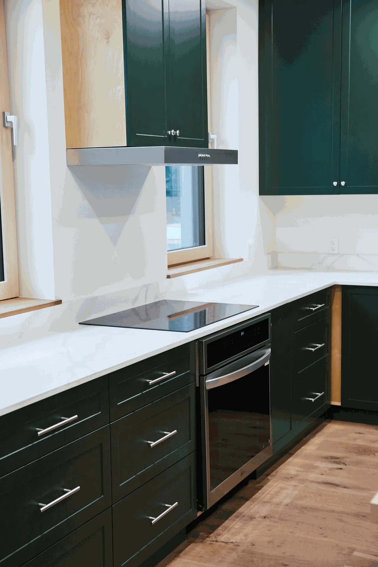 Close-up view of a modern kitchen featuring dark green cabinetry, stainless steel appliances, and a sleek countertop.