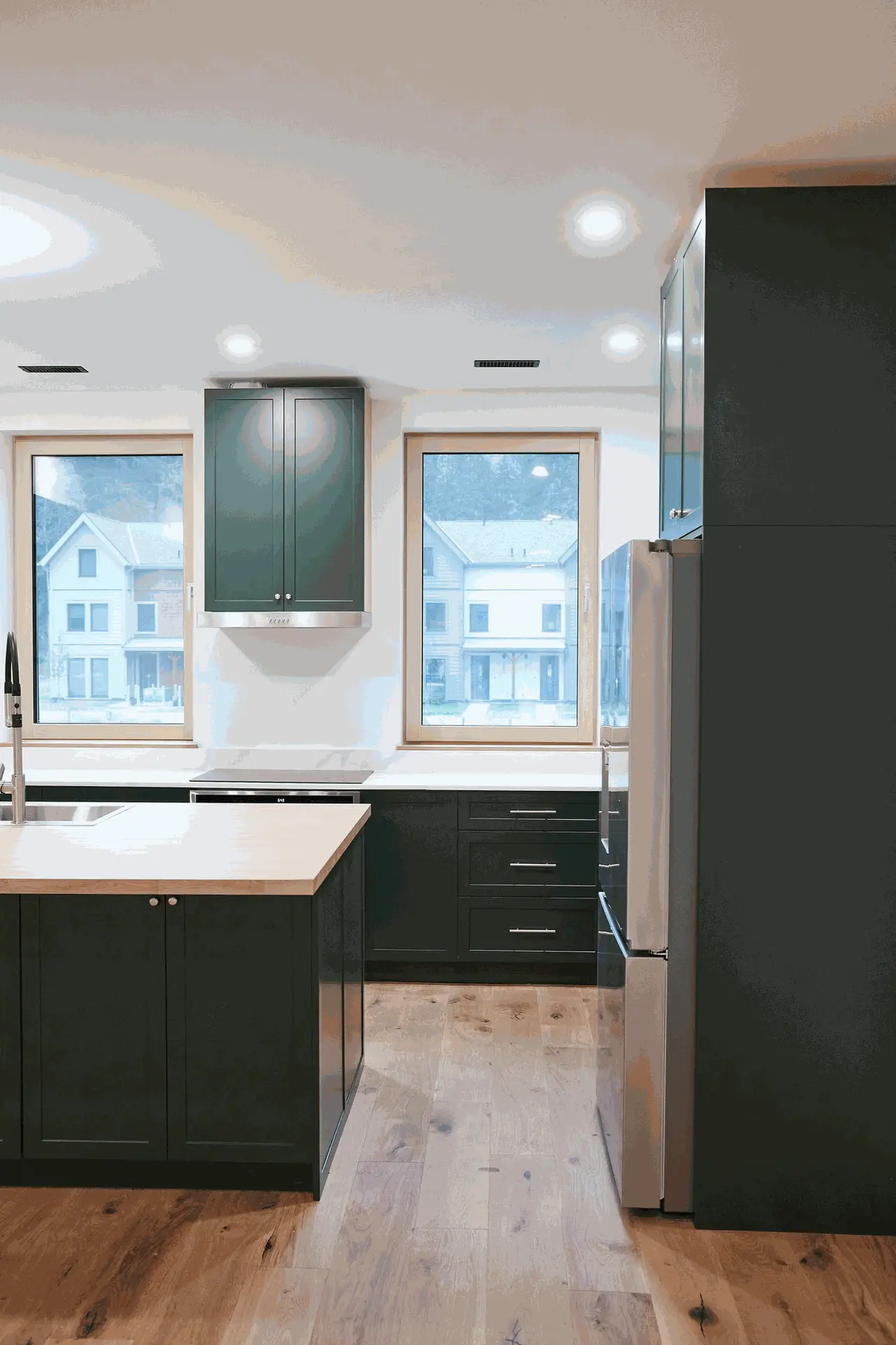 Spacious kitchen featuring dark green cabinetry, a central island with a light wood countertop