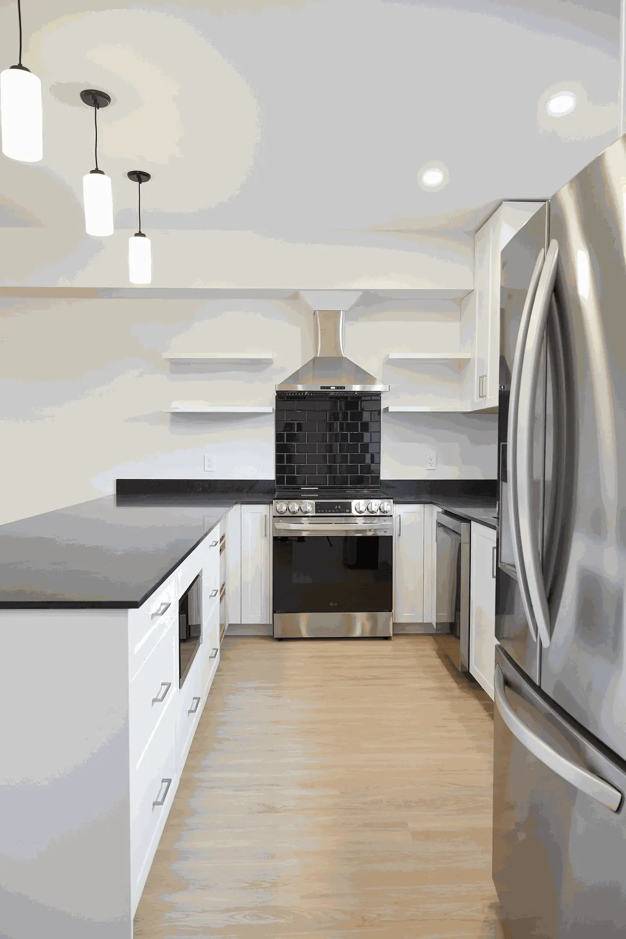 Modern kitchen design featuring white cabinets, sleek black countertops, a stainless steel oven