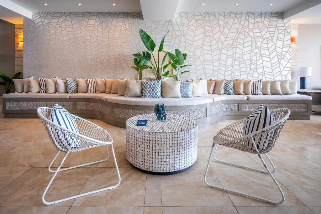 Inviting lounge area featuring a spacious sectional sofa, stylish accent chairs, and a decorative coffee table surrounded by tropical plants.
