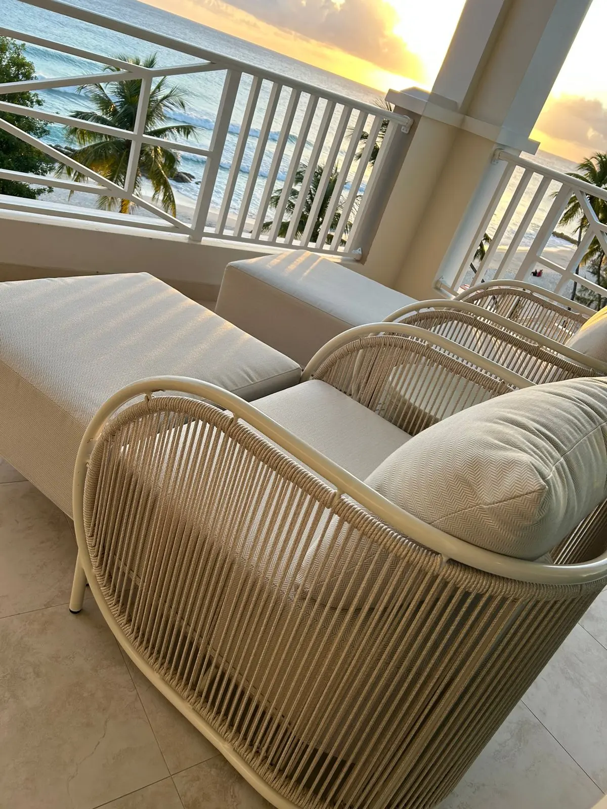 Elegant outdoor seating with a view of the ocean at sunset, featuring stylish loungers and a peaceful atmosphere.