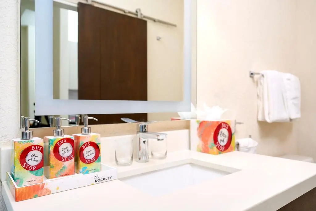Stylish bathroom vanity at The Rockley, featuring colorful soap dispensers, modern fixtures, and elegantly designed accessories.
