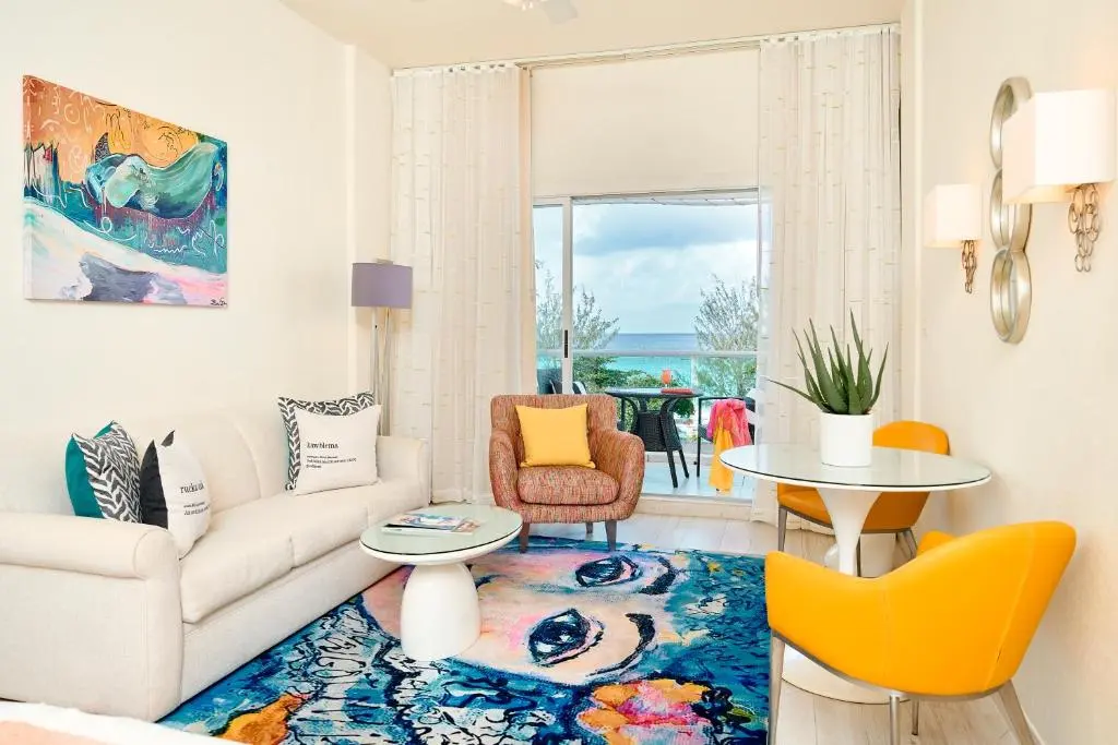 Cheerful living area at The Rockley featuring a light sofa, colorful art, bright yellow chairs