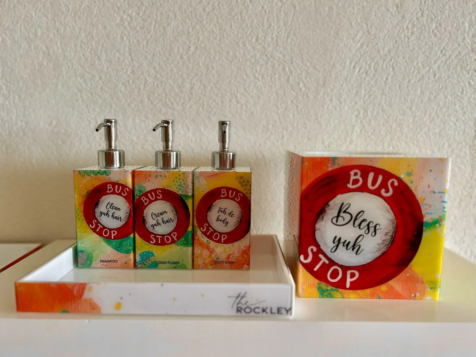 Vibrant toiletries set at The Rockley featuring shampoo, conditioner, and body wash bottles with playful designs and labels.