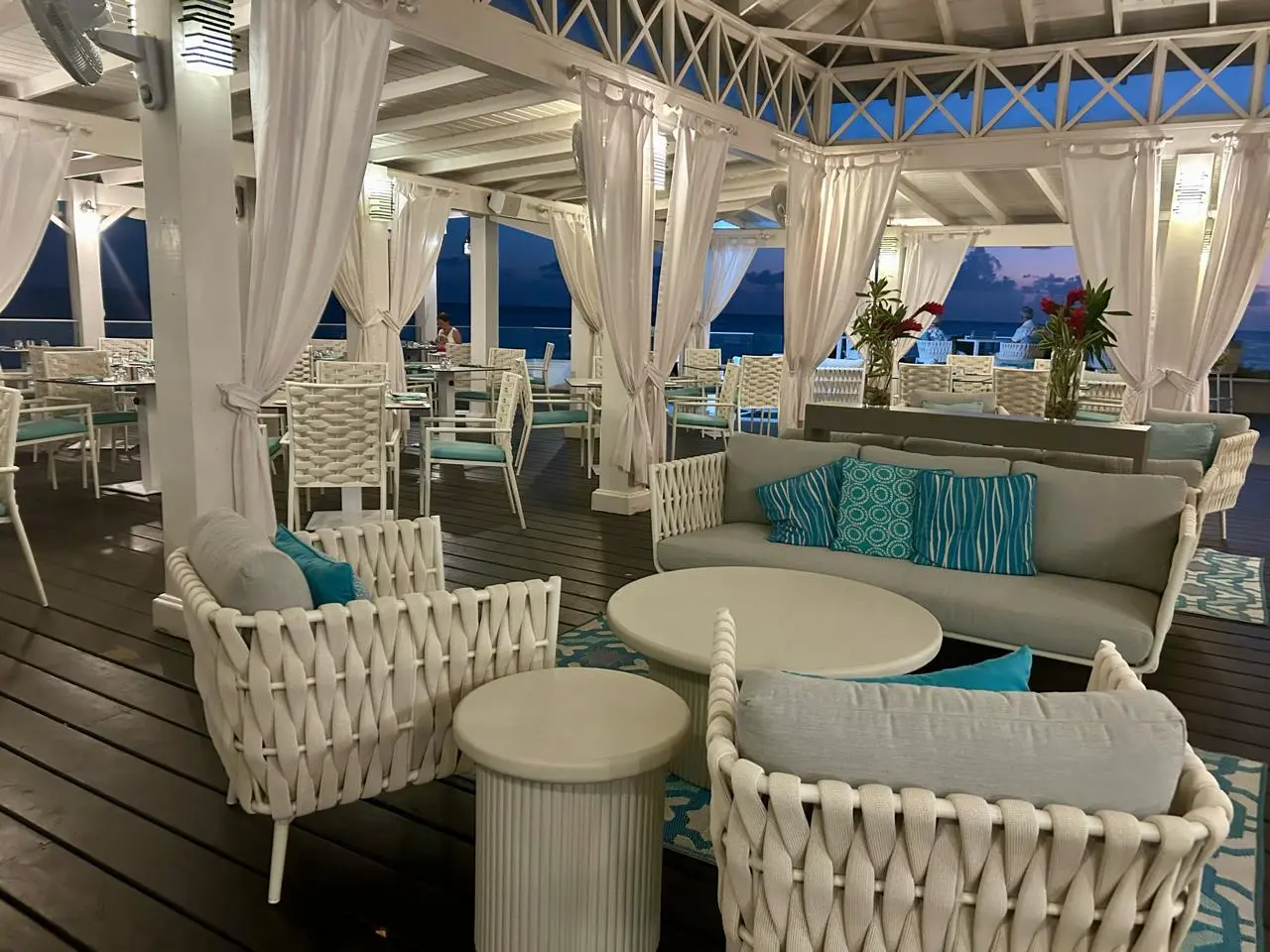Cozy lounge area at Aqua Terra Restaurant featuring white wicker furniture, colorful cushions