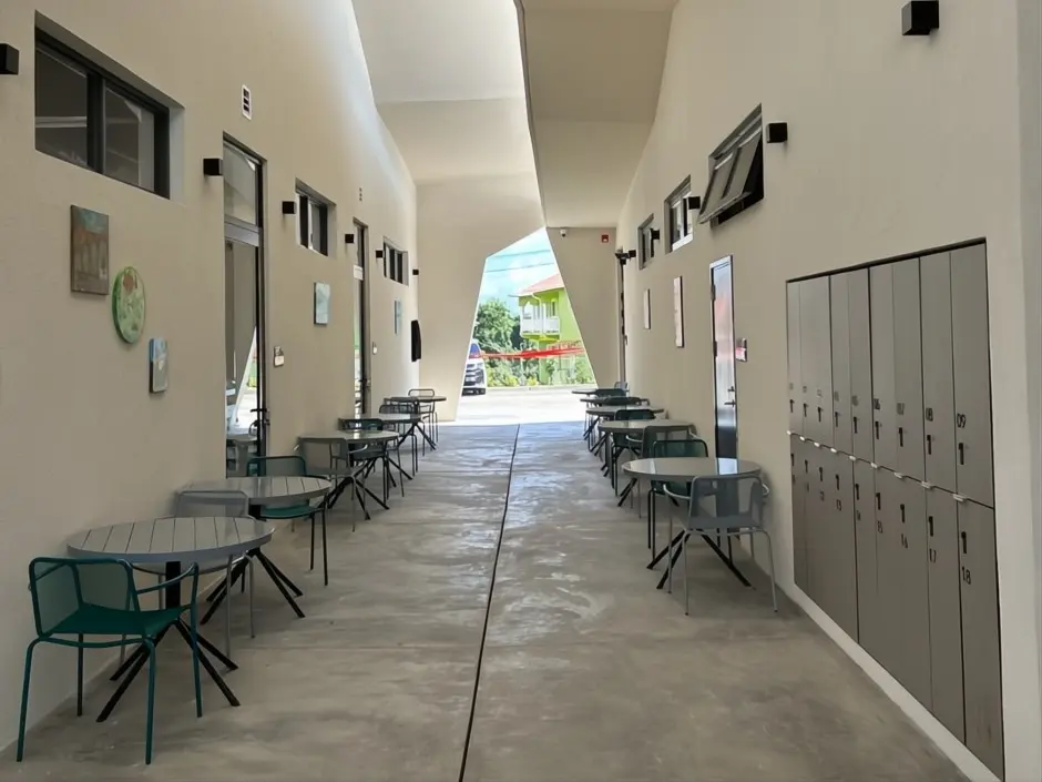 Bright corridor at SJSM Pre-Med featuring tables and chairs for student relaxation, along with storage lockers and decorative wall art.