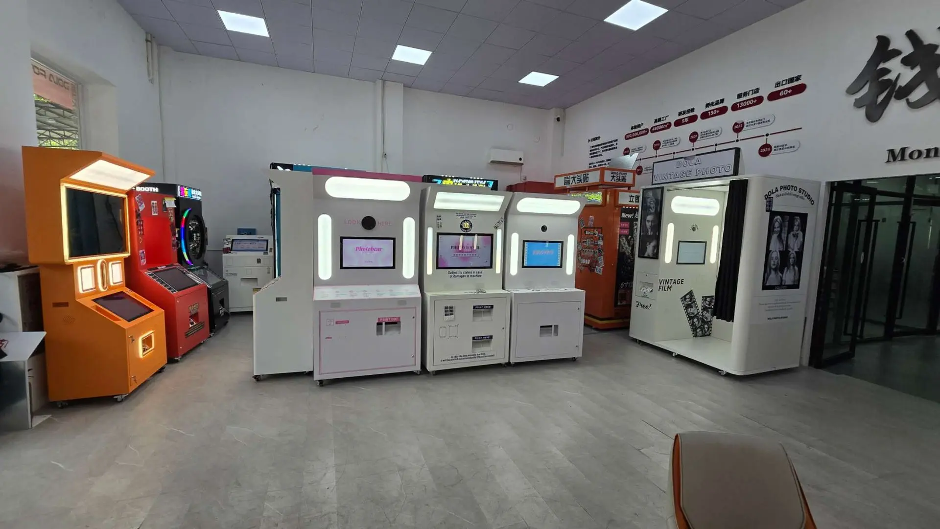 A row of self-service kiosks and machines lined up against a wall in a brightly lit indoor area with tiled flooring.