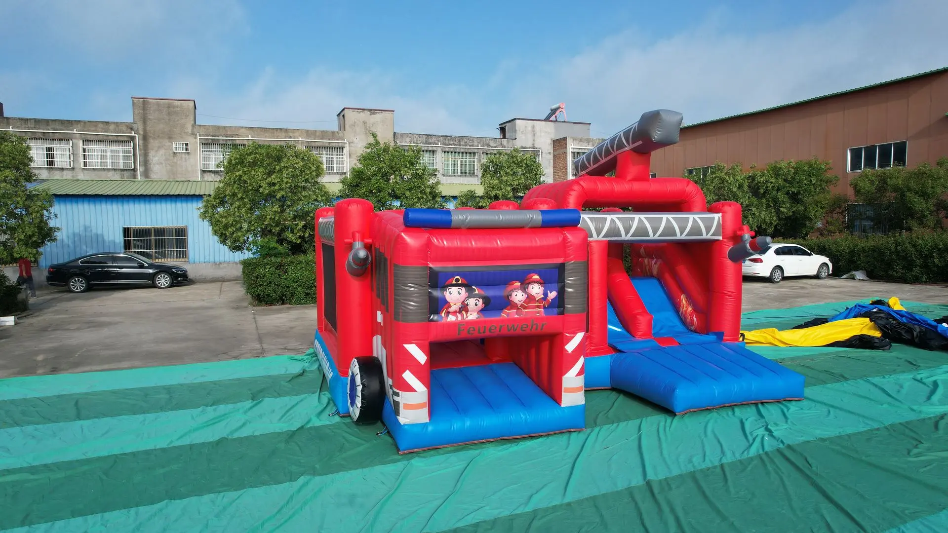 Fire Truck Themed Inflatable Obstacle Course with Dual Slides Large red inflatable fire truck-themed obstacle course with blue slides, gray ladders, and cartoon firefighters on the front