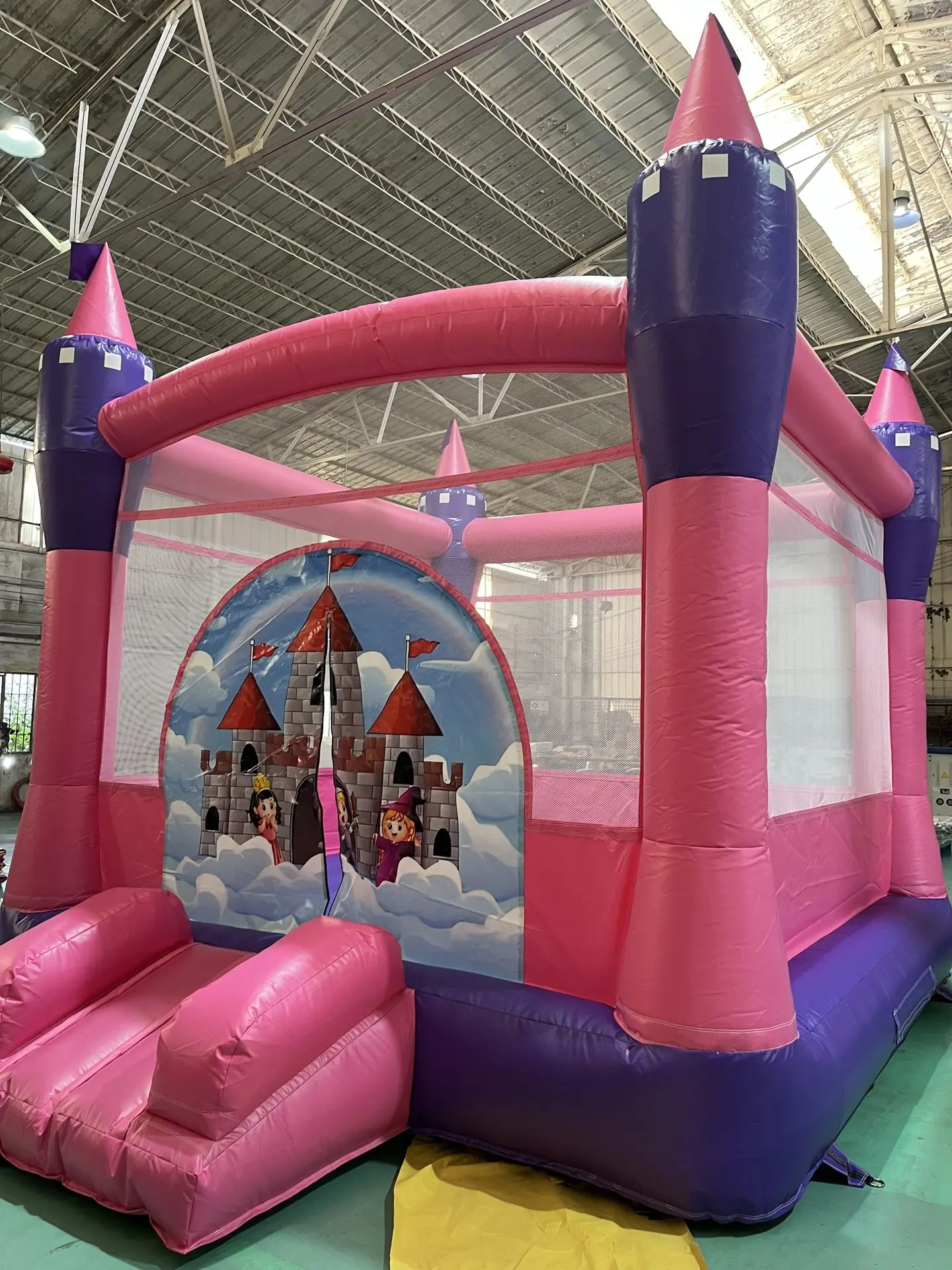 ink & Purple Castle Inflatable Bounce House with Turrets pink and purple inflatable castle-style bounce house with tall turret-like columns, a pink entrance ramp, pink framing, and a castle graphic on the front panel