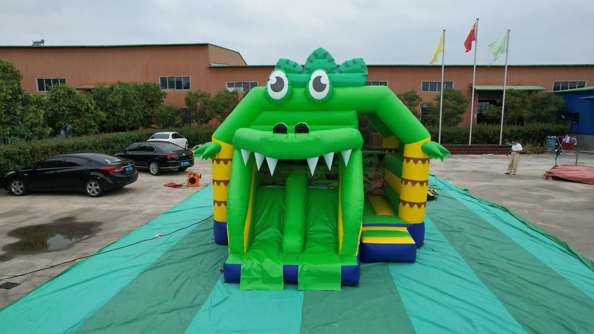 Inflatable Crocodile Bounce House A bright inflatable crocodile-themed bounce house with a wide open mouth, large eyes, and yellow and purple accents; set up outdoors