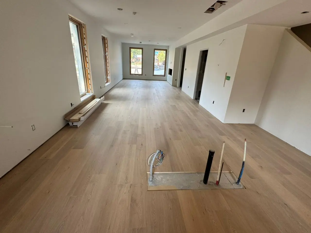Open-concept living area under construction with light timber flooring