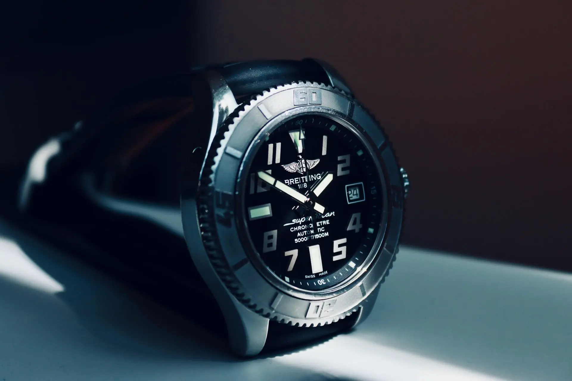Premium Automatic Diver Watch A close-up of a Breitling wristwatch with a black dial, large numerals, and a black strap, resting on a white surface.