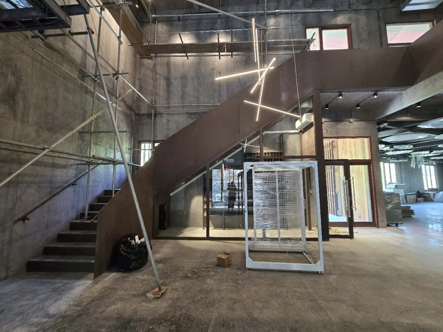 Custom Metal Staircase for Secret Bay's Art Barn Amenities Building Custom metal staircase under construction in an industrial-style building, with a curved profile, steel railings, and exposed concrete walls.