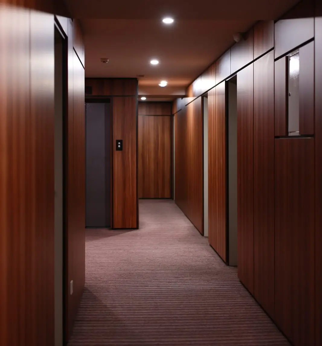 Interior hallway with dark wood wall panels and recessed ceiling lights..