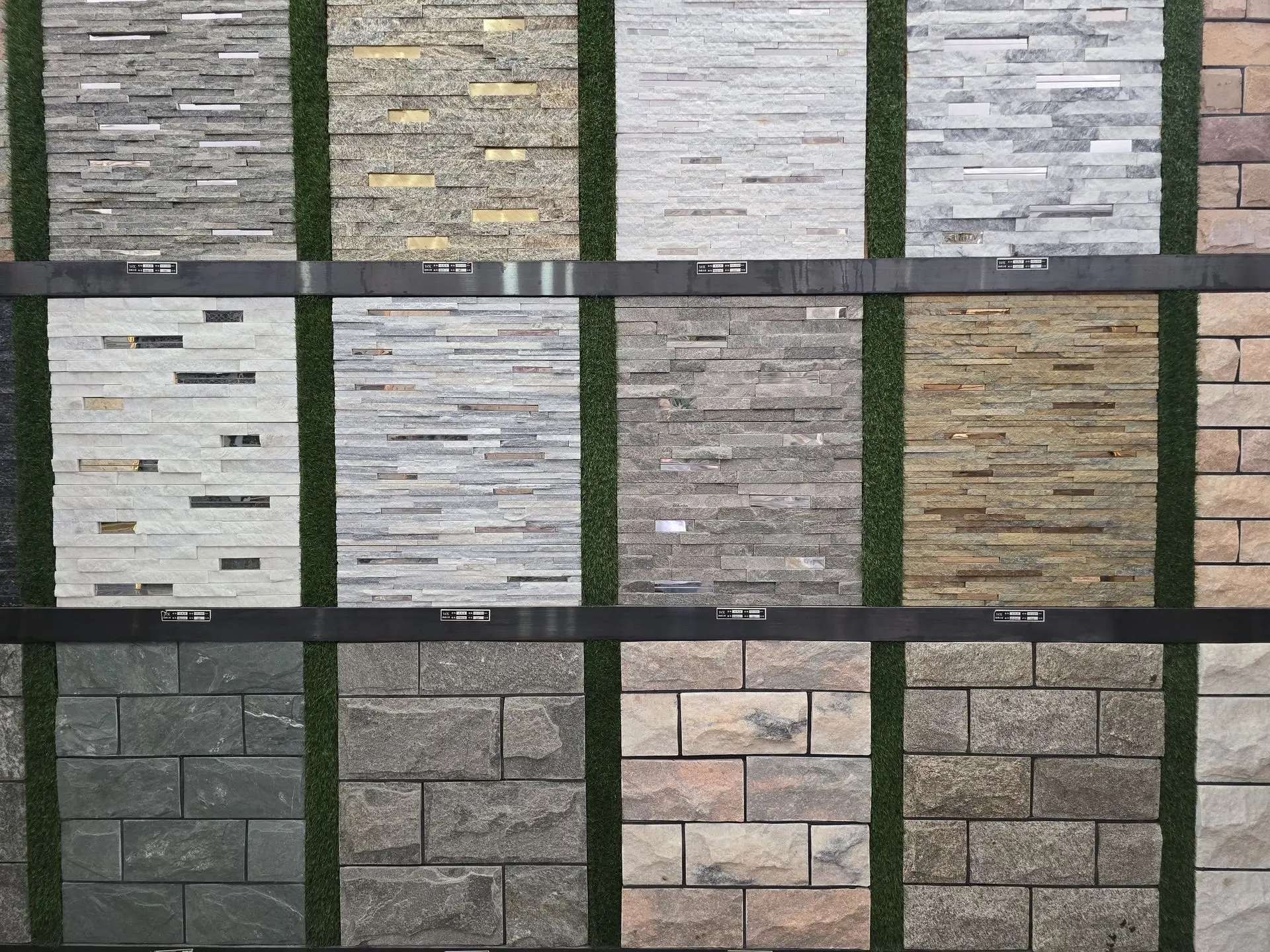 Display of various stone wall cladding samples arranged in vertical panels with different textures and colors.