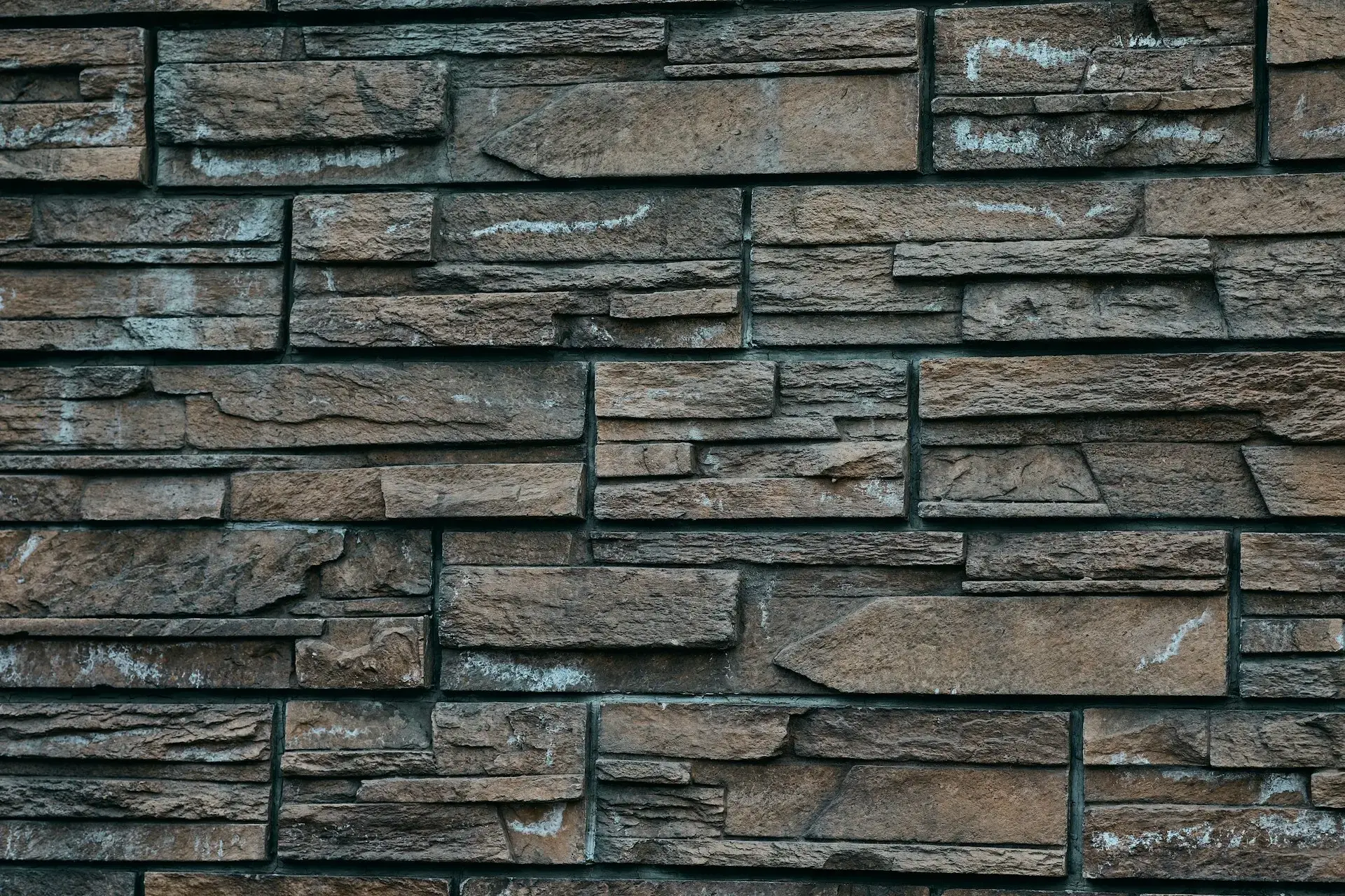 ustic stacked stone wall cladding in varying shades of brown and gray, showcasing natural texture and architectural distinction for luxury interior or exterior projects.