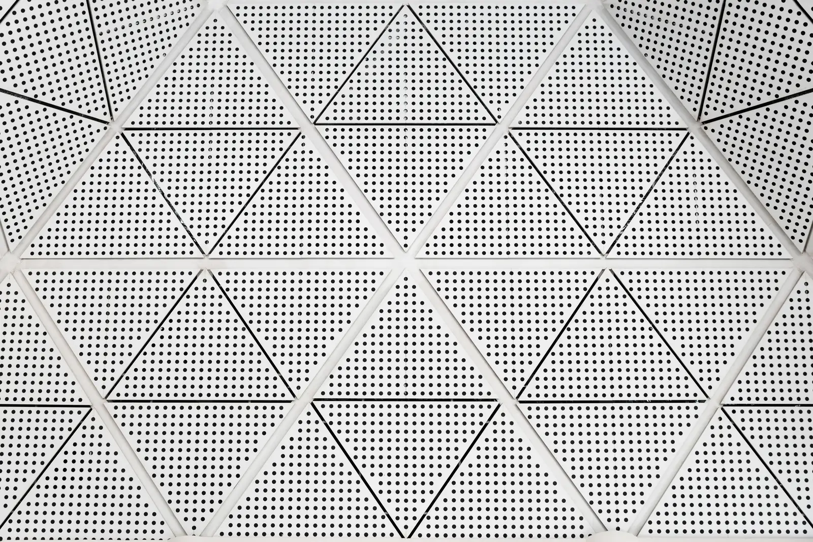 Aluminum Ceiling Systems: Durable, Lightweight, and Customizable for Modern Interiors Close-up of an aluminum ceiling system with geometric triangular perforated panels and light, showcasing a modern, durable, and stylish interior finish.