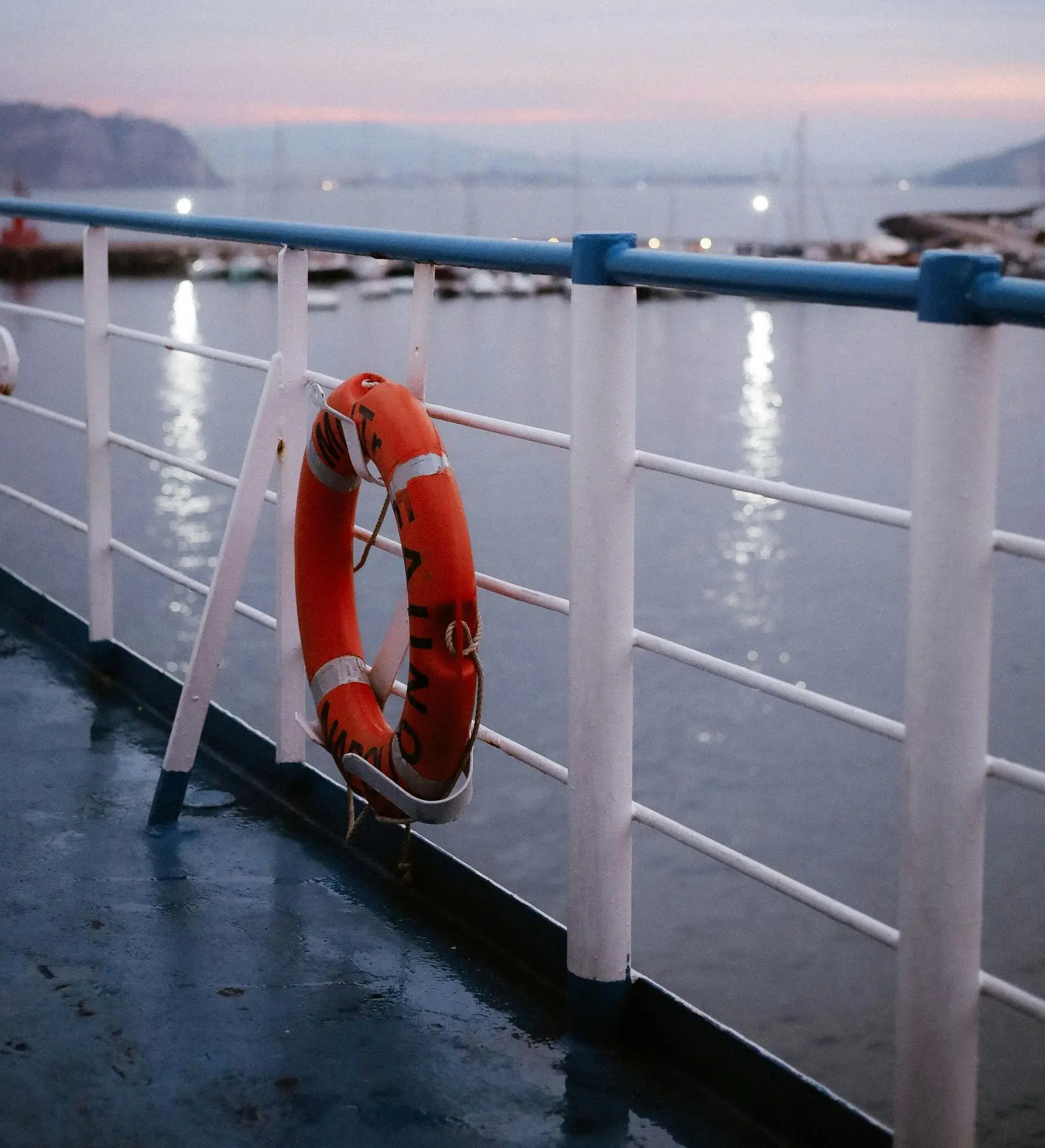 Composite and PVC railing on a waterfront deck with a safety life ring attached to the railing, overlooking a harbor.
