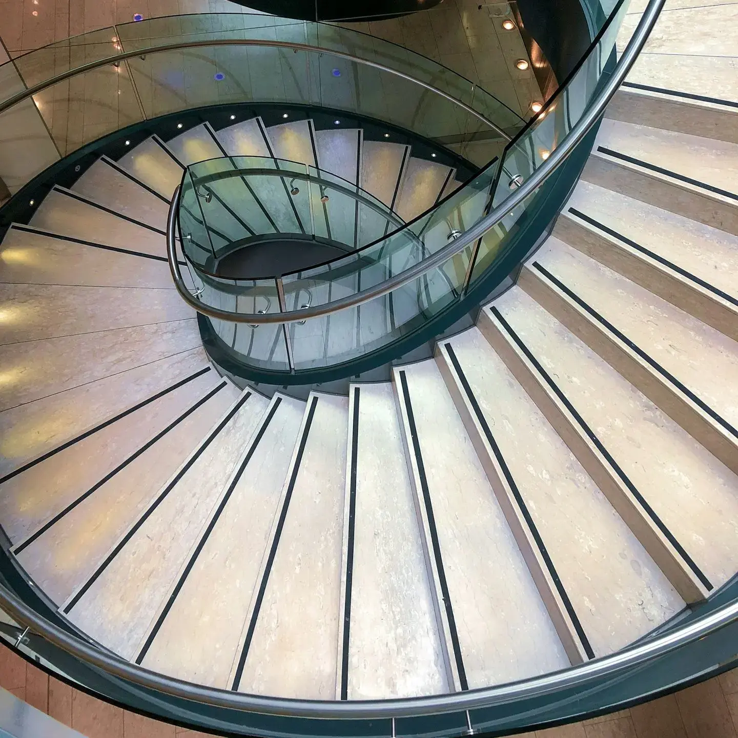 Spiral glass-rail China staircase interior Modern Chinese interior with a circular glass-rail staircase descending through multiple levels.