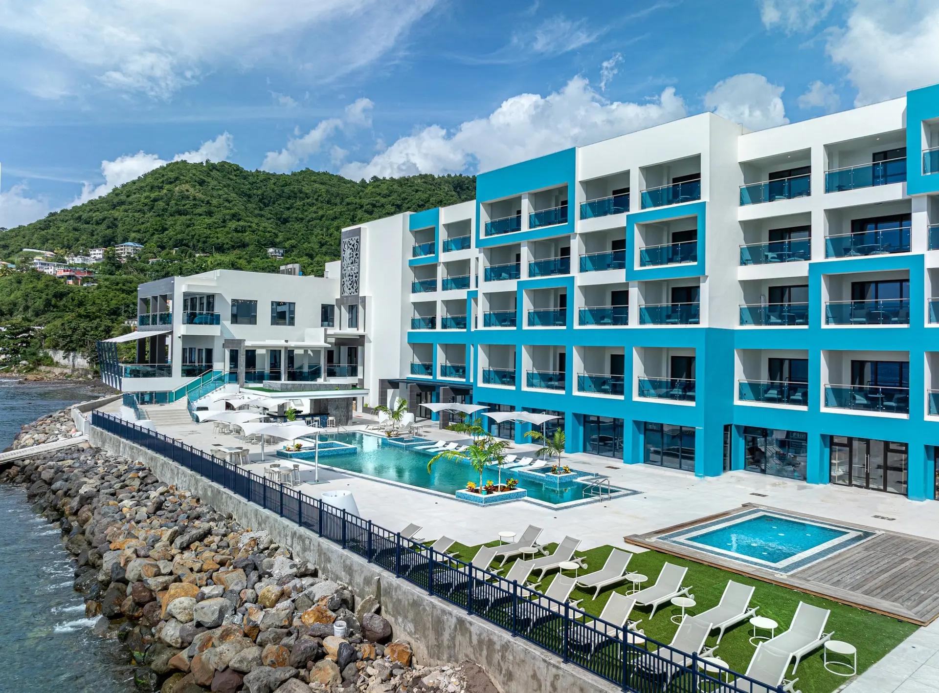 Ocean Oasis Hotel exterior showcasing the white and turquoise modern building, infinity pool, lounge deck, and spa area, all furnished with GZS-sourced outdoor FF&E.