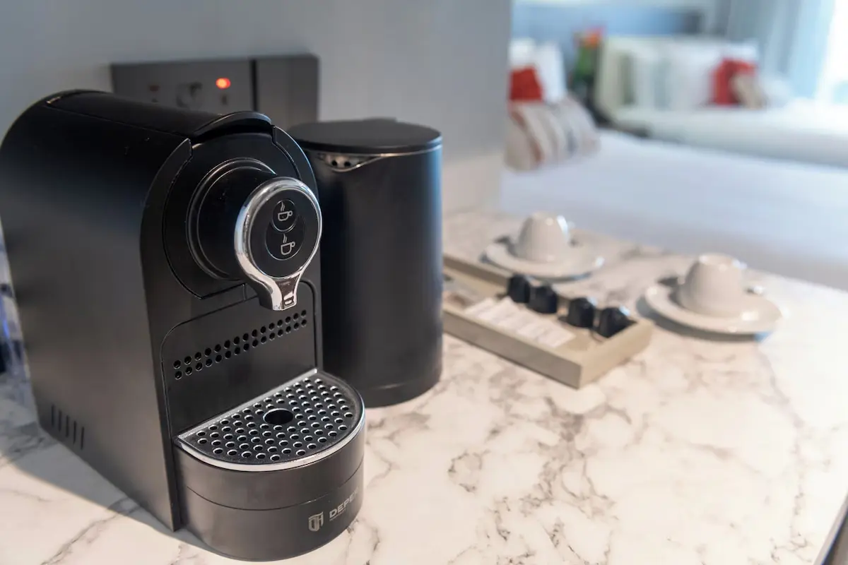Premium In-Room Amenities - GZS Sourced OS&E Close-up of a premium coffee station in an Ocean Oasis Hotel suite, including an espresso machine and cups, highlighting GZS-sourced OS&E amenities.