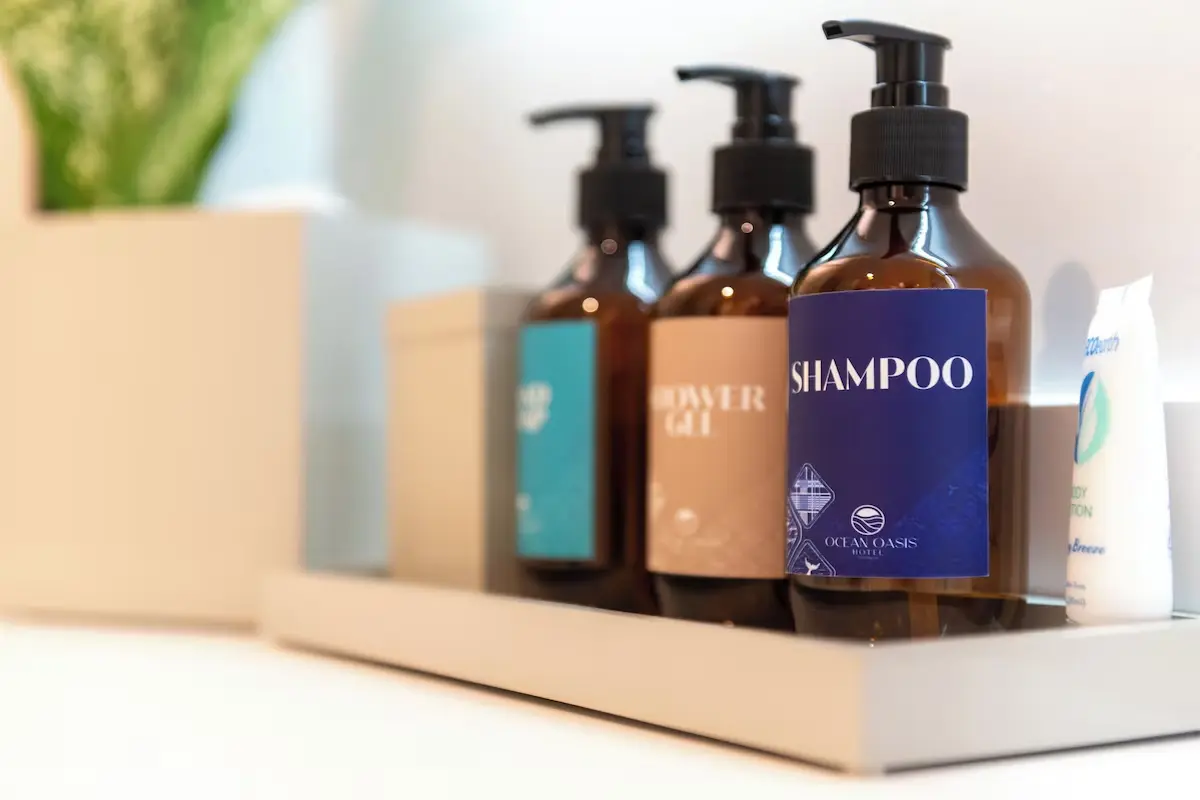 Branded Bathroom Toiletries - GZS Amenity Procurement In-room guest amenity set with branded shampoo, conditioner, and body wash bottles on a tray, provided through GZS amenity sourcing.