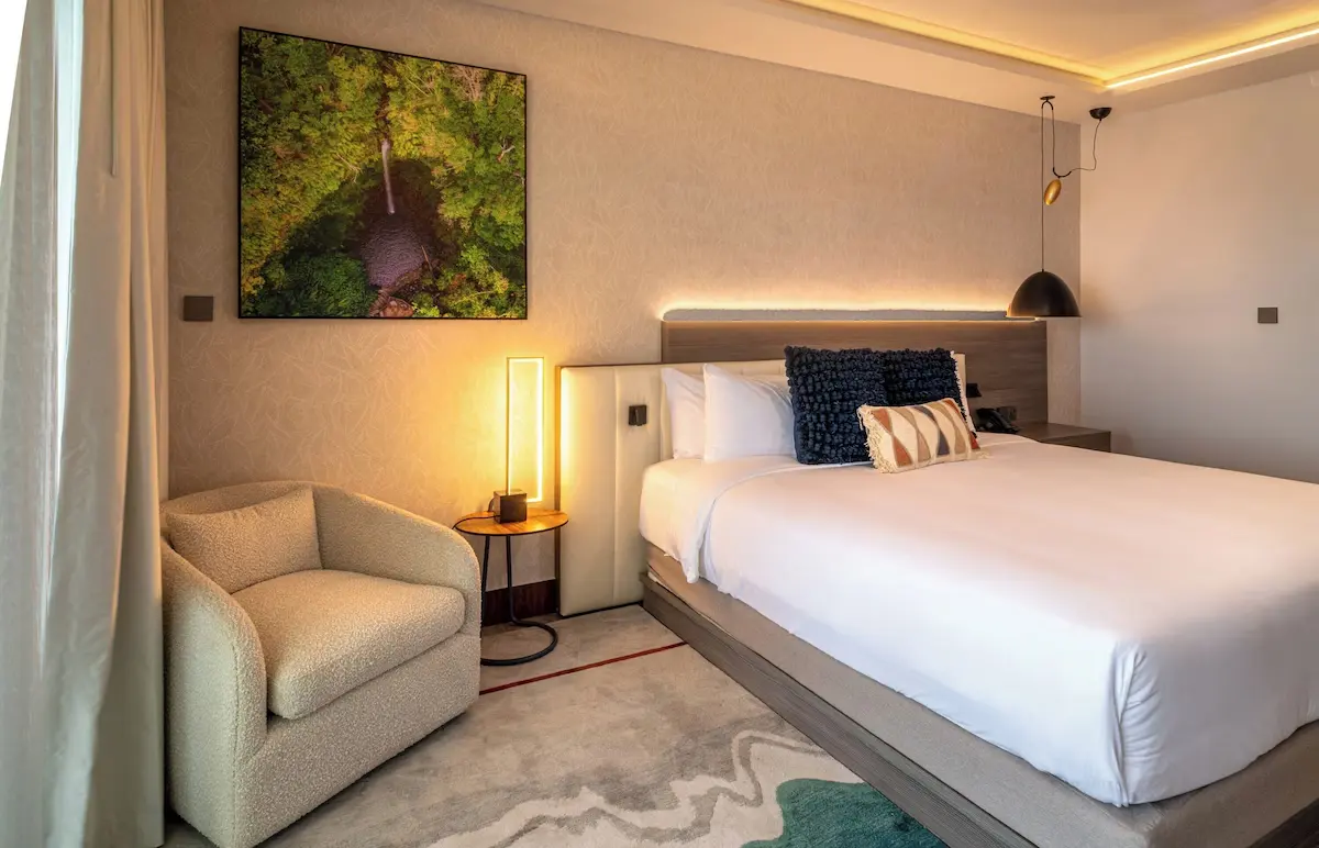 Deluxe Guest Room - GZS Furnishings and Lighting Ocean Oasis Hotel guest room featuring a plush, queen-sized bed, stylish lighting, and a modern armchair, showcasing GZS-sourced FF&E.