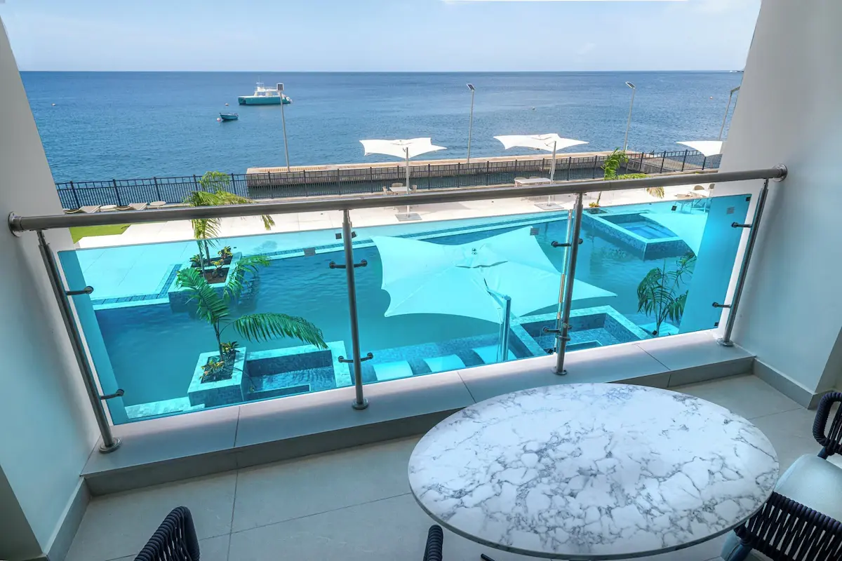 Ocean Oasis Hotel Balcony with Glass Railing and Marble Furniture Guest room balcony with a glass railing and small marble table overlooking the ocean and the pool, featuring GZS-sourced balcony furniture.