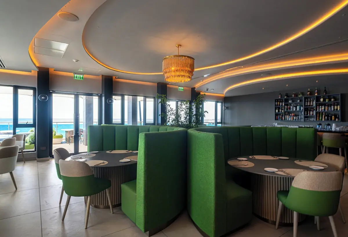 Restaurant Booths and Seating - GZS Custom FF&E Ocean Oasis Hotel dining area featuring large green custom booths, small tables, chairs, and custom chandeliers, supplied entirely through GZS procurement.